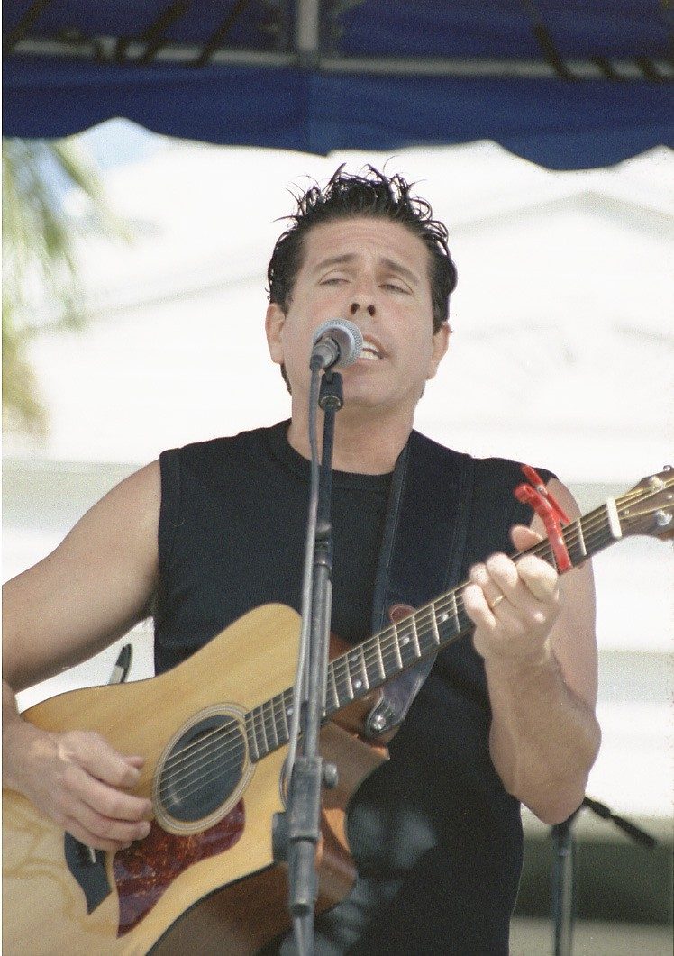 Tim McGeary singing and playing acoustic guitar at an outdoor show